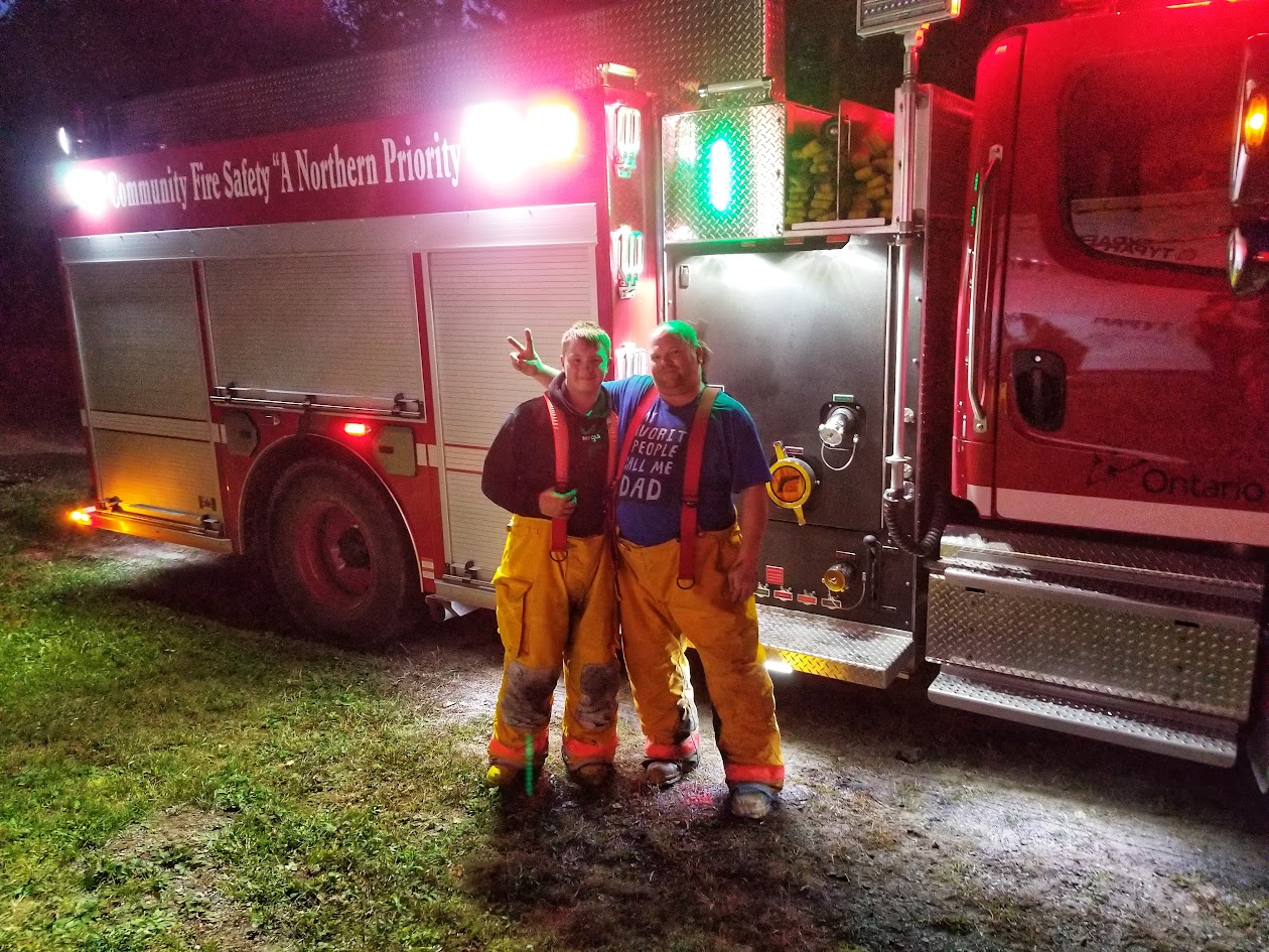 Two SCVFD firefighters in bunker pants beside the pumper at night