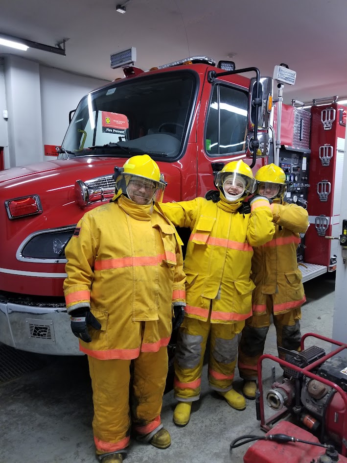 Three visitors in full turnout gear in front of the pumper