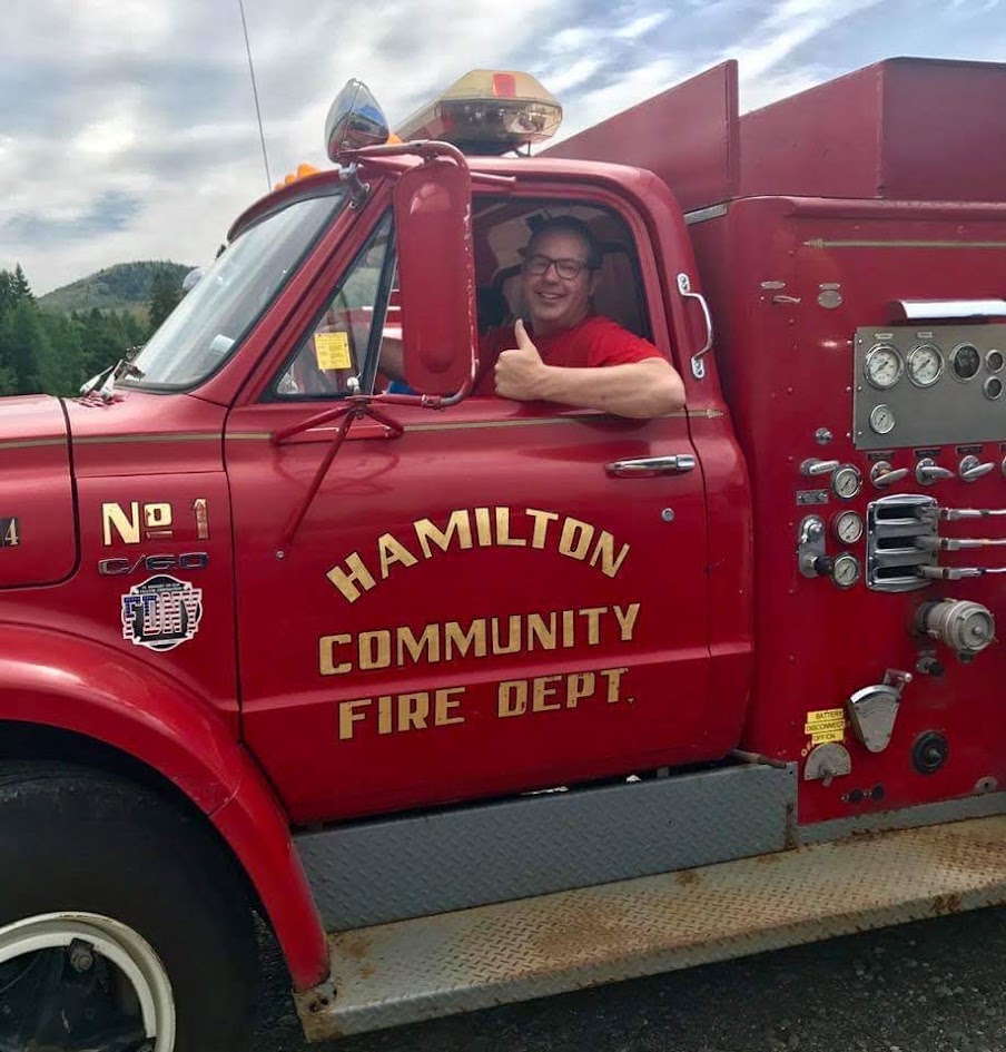 Travis McCormack giving a thumbs up from the cab of a vintage Hamilton Community Fire Dept truck