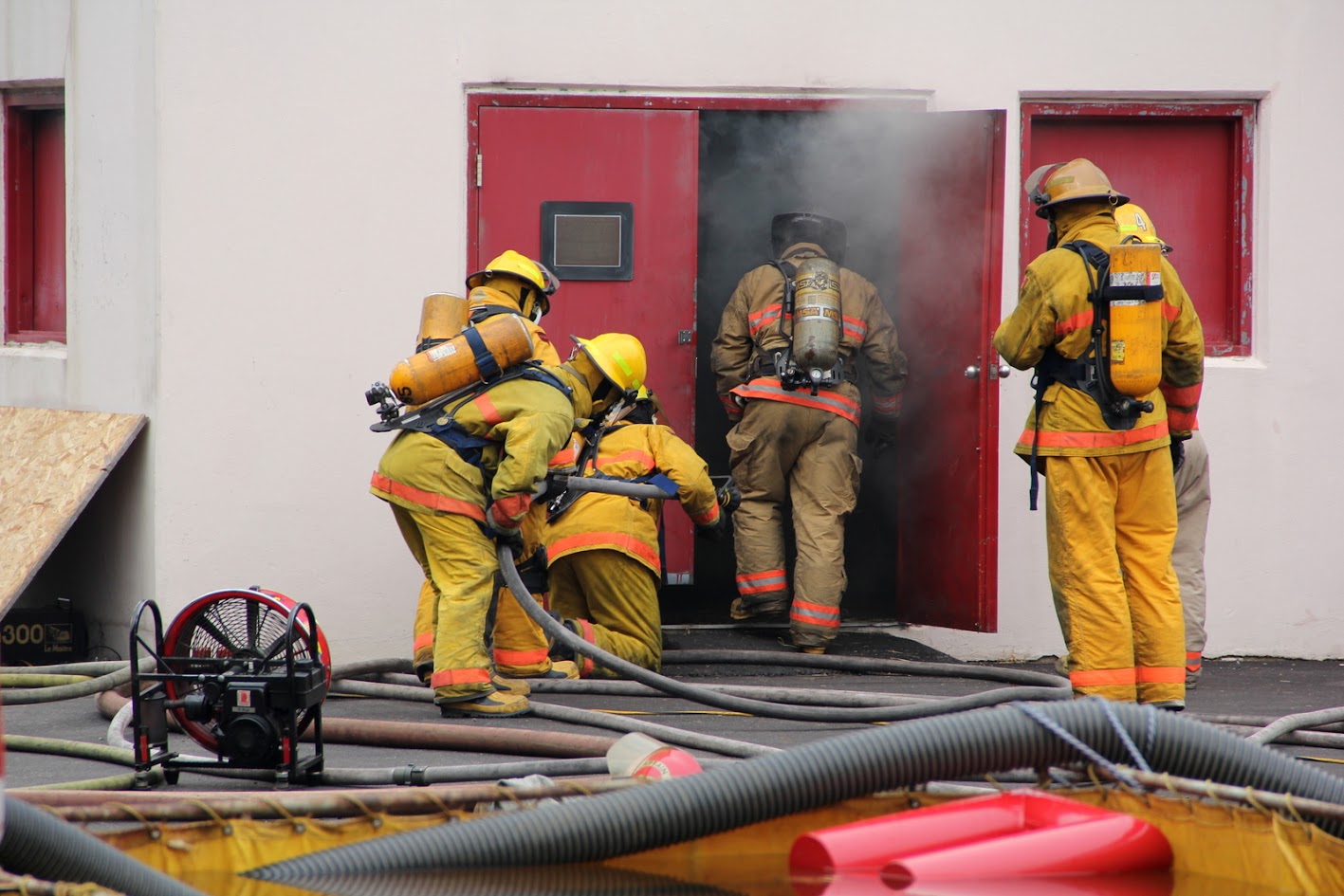 Firefighters on air advancing a hose line into a smoking burn building