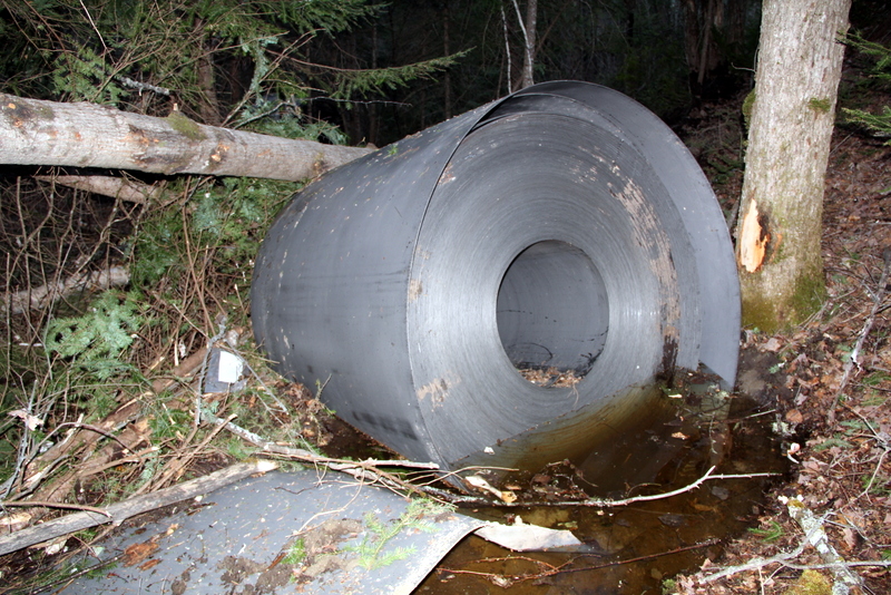 Steel coil thrown from the train lying in the woods in standing water