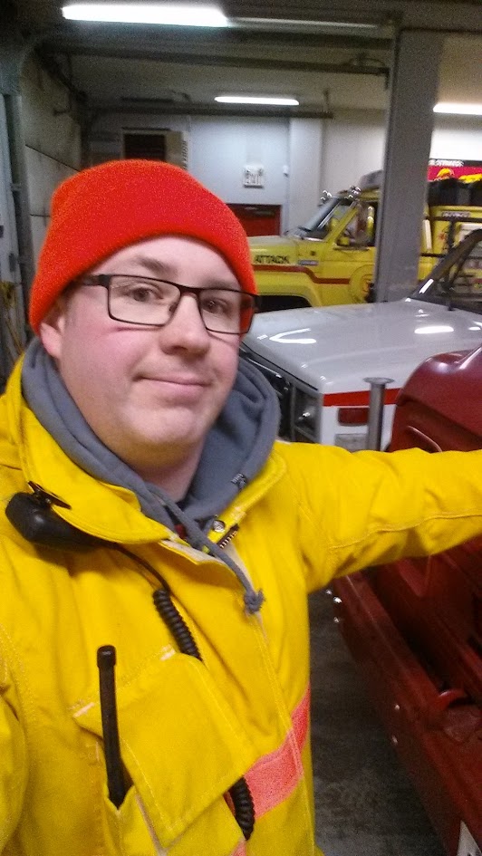 Travis McCormack in turnout coat and radio in the apparatus bay