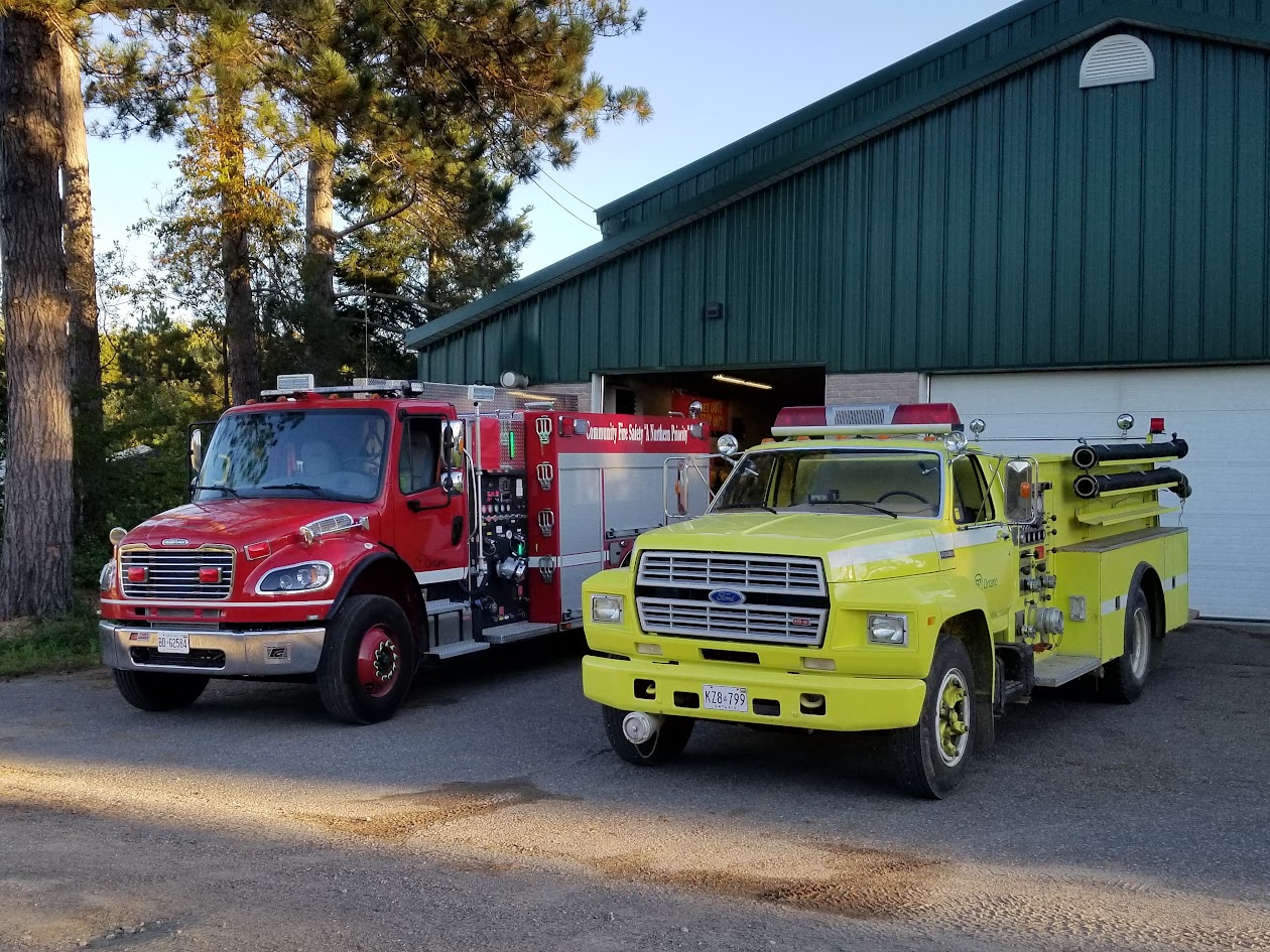 Red pumper reading Community Fire Safety A Northern Priority beside a yellow Ford pumper